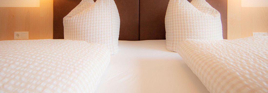 A cozy bedroom with two beds and bright pillows. The walls are designed in warm tones, and soft lighting creates an inviting atmosphere. - Haus Montjola - Sölden