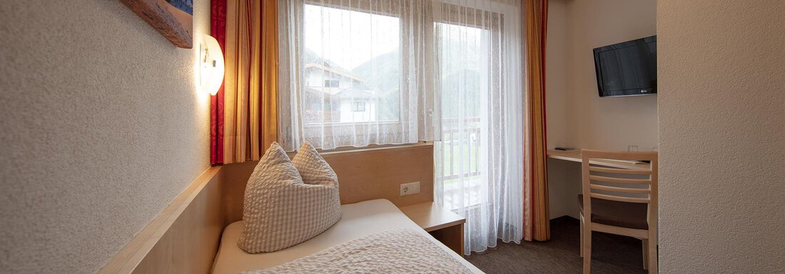 Beispiel Einzelzimmer A cozy room with a single bed, a desk, and a television. Large windows provide plenty of daylight and a view outside. - Haus Montjola - Sölden
