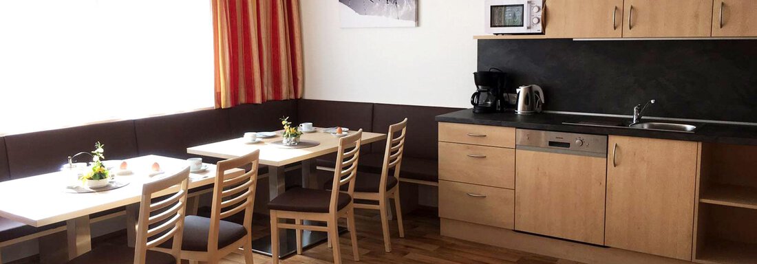 Wohnküche A bright kitchen with wooden floors and modern furniture. There is a dining table with chairs as well as a functional kitchenette. - Haus Montjola - Sölden