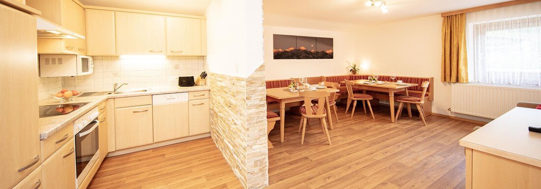 Wohnküche A modern, bright kitchen with a wooden floor and an open dining area. The furniture is functional and inviting, perfect for social moments. - Haus Montjola - Sölden