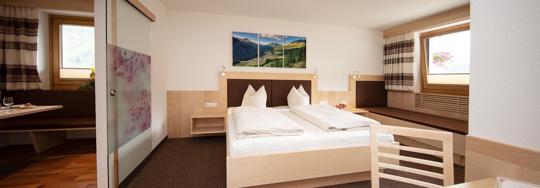 Schlafzimmer A cozy hotel room with two beds and wooden paneling. Large windows provide plenty of daylight and a view of nature. - Haus Montjola - Sölden