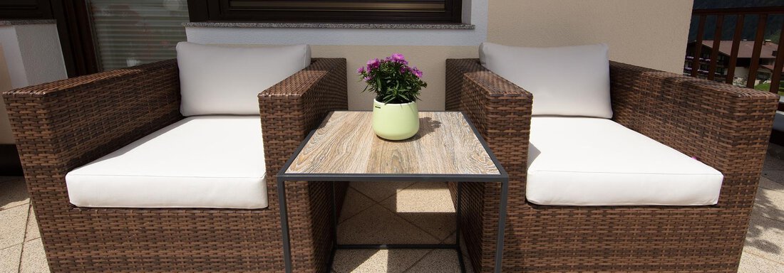 Two cozy chairs with white cushions are next to a small table. On the table stands a pot with a blooming plant. - Haus Montjola - Sölden