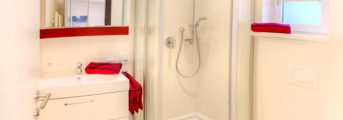 A modern bathroom with a shower and a sink. Red towels add a splash of color to the room. - Haus PIA by A CASA - Sölden