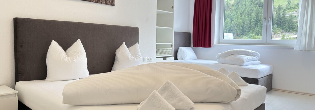 A modern bedroom with a double bed and a single bed. Bright walls and large windows create a friendly atmosphere. - Haus PIA by A CASA - Sölden