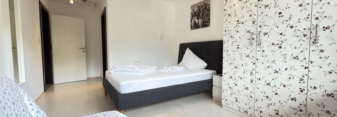 A modern bedroom with a double bed and a white wardrobe. There is an armchair and a bright, friendly room with natural light. - Haus PIA by A CASA - Sölden