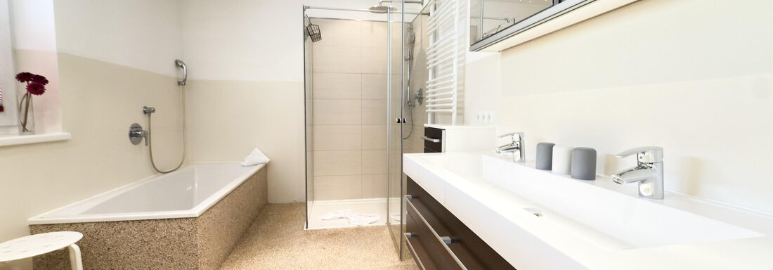 A modern bathroom with a bathtub and a shower. The furniture is in an elegant dark brown and there are large mirrors. - Haus PIA by A CASA - Sölden