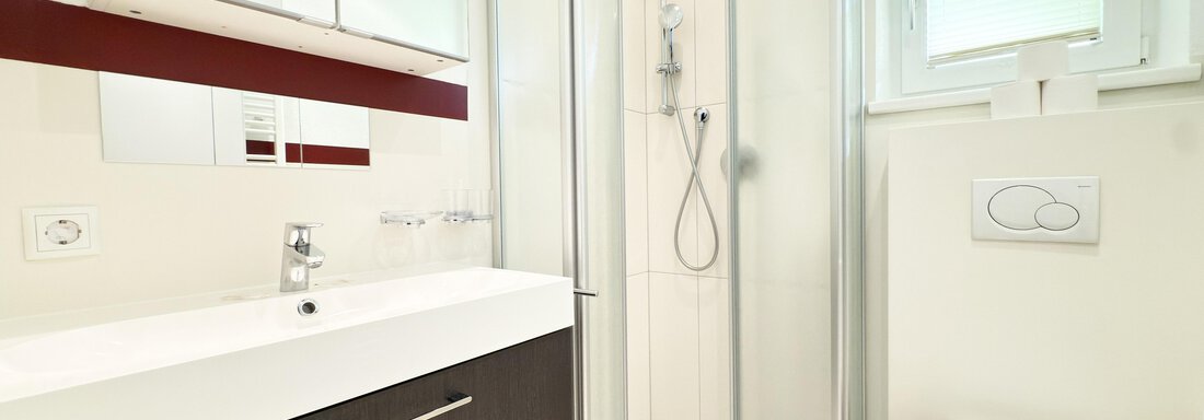 A modern bathroom with a shower, a sink, and a toilet. The walls are bright and the furnishings are simple and elegant. - Haus PIA by A CASA - Sölden