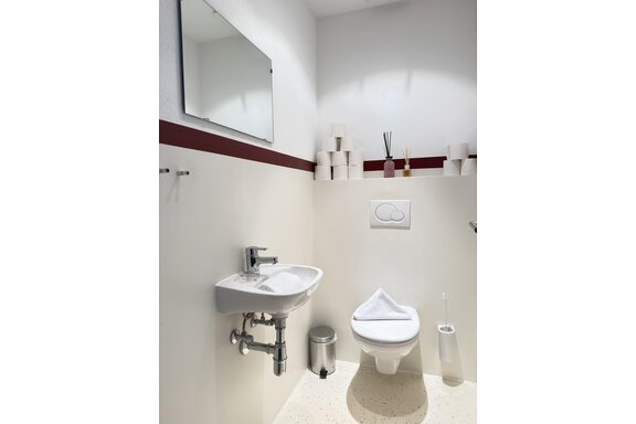 A modern bathroom with a sink, a toilet, and a mirror. The walls are in light tones, with decorative elements. - Haus PIA by A CASA - Sölden