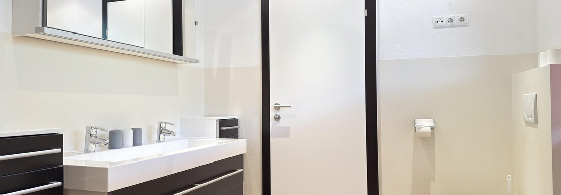 A modern bathroom with an elegant sink and large mirrors. The walls are light and the decor is functional and stylish. - Haus PIA by A CASA - Sölden
