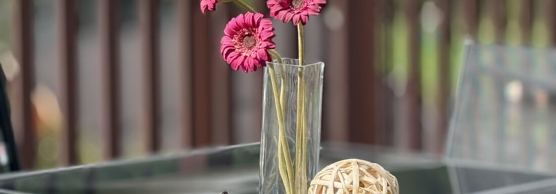 An elegant arrangement with pink flowers in a glass vase. Next to it, there are decorative balls on a black table. - Haus PIA by A CASA - Sölden
