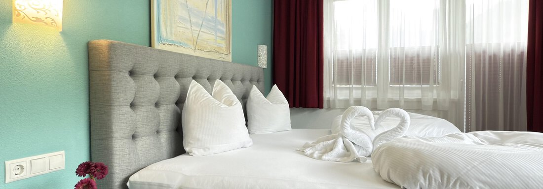 A modern bedroom with a large bed and stylish pillows. The walls are painted in a calming blue, and large windows let in plenty of light. - Haus PIA by A CASA - Sölden