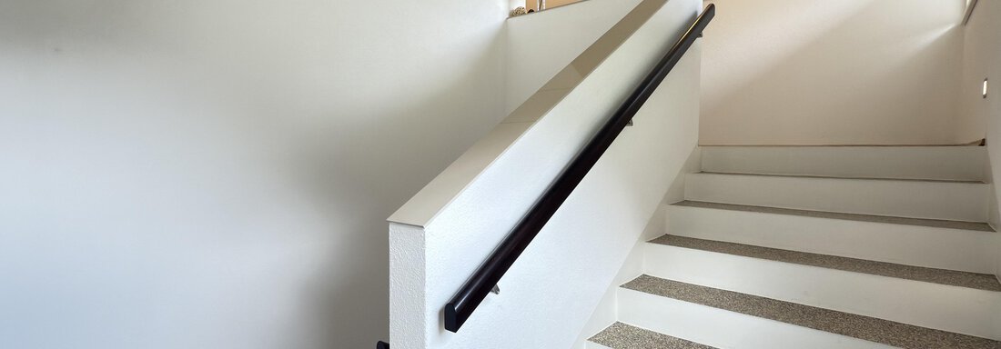 A bright staircase with a white wall and a handrail. The floor is carpeted and the area is well-lit. - Haus PIA by A CASA - Sölden