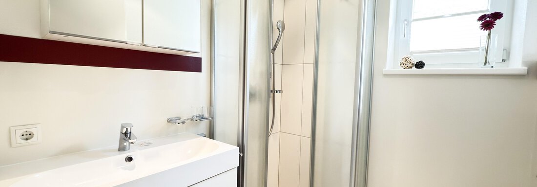 A modern bathroom with a shower cabin and a white sink. The room is bright and friendly designed, with a window and a small stool. - Haus PIA by A CASA - Sölden