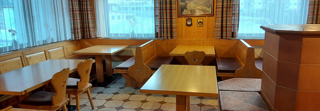 A cozy dining area with wooden furniture and large windows. The decor is rustic and inviting. - Haus Pitzwald - Sölden