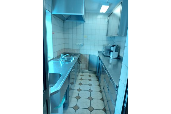 A modern kitchen with stainless steel countertops and tiled flooring. White tiles are placed on the walls along with various kitchen appliances. - Haus Pitzwald - Sölden