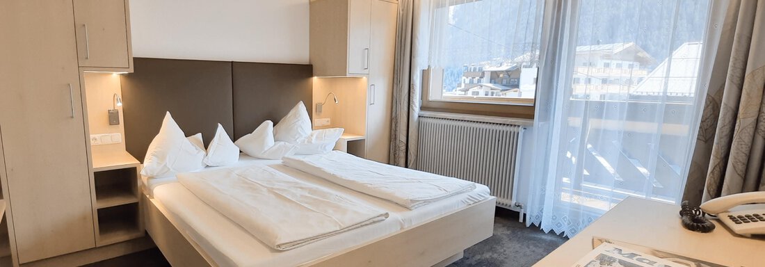 Doppelzimmer mit Ostbalkon A modern bedroom with two beds and large windows. The decor is bright and elegant, with plenty of natural light. - Haus Rehwinkl - Sölden