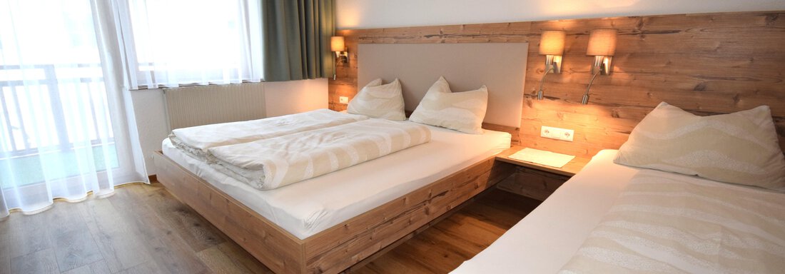 A cozy bedroom with two beds and wooden details. Large windows provide plenty of daylight and a pleasant atmosphere. - Haus Romana - Sölden