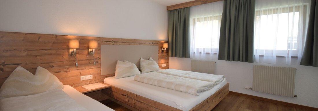 A bright room with two beds and wooden details. Large windows let in plenty of daylight. - Haus Romana - Sölden