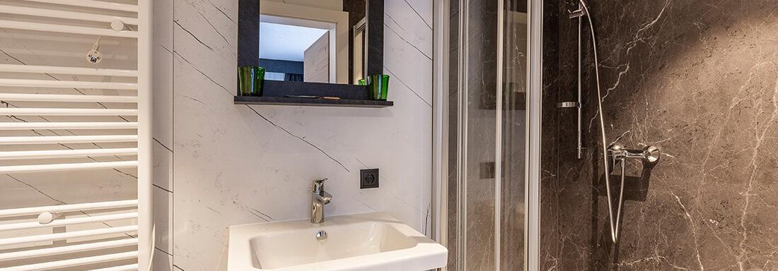 A modern bathroom with a shower and a sink. The walls are in elegant black and white, complemented by green accents. - Haus Sieglinde Color - Sölden