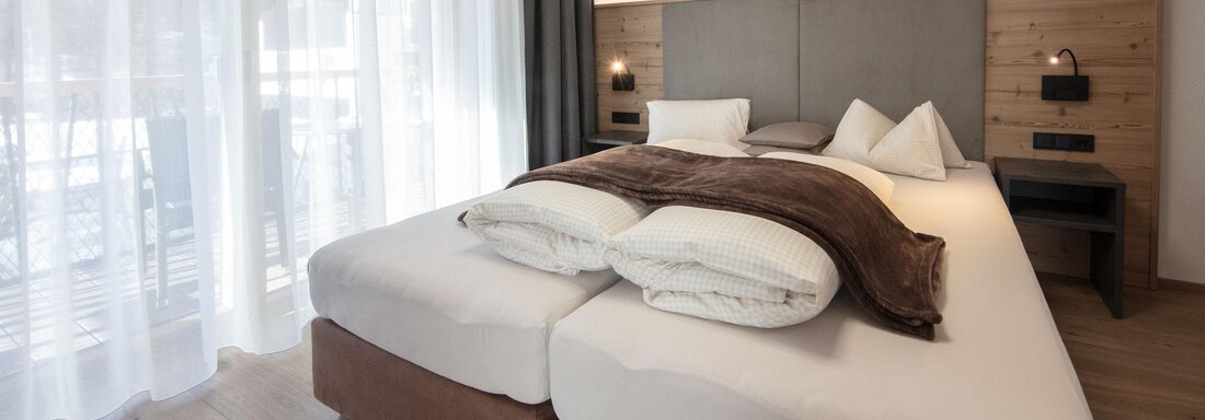 Zimmer | © CI-CENTER (CC C) A modern bedroom with a large bed and cozy bedding. Bright curtains let in plenty of light and create an inviting atmosphere. - Haus Sonnwend - Sölden