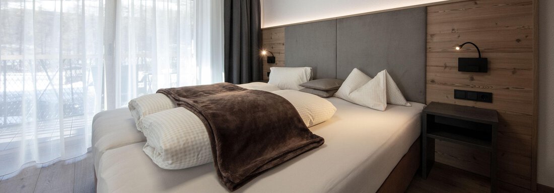 A modern bedroom with a large double bed and cozy bedding.  
Large windows provide plenty of natural light and a welcoming atmosphere. - Haus Sonnwend - Sölden