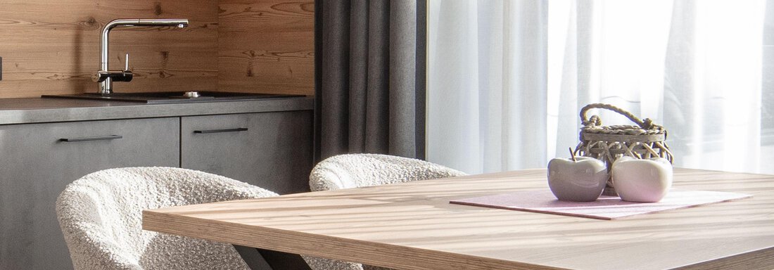 A modern dining area with a wooden table and comfortable chairs. The kitchen corner is designed in a minimalist and bright style. - Haus Sonnwend - Sölden