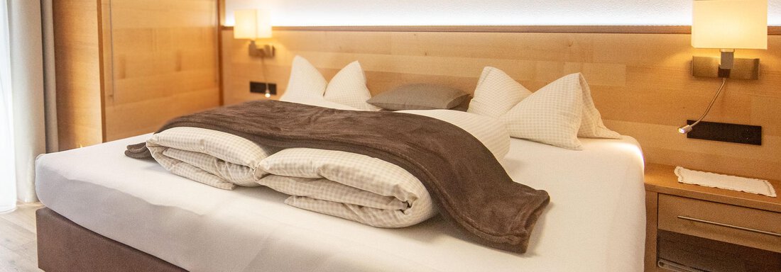 A cozy bedroom with a large bed and stylish wooden furniture. Soft lighting creates a relaxed atmosphere. - Haus Sonnwend - Sölden