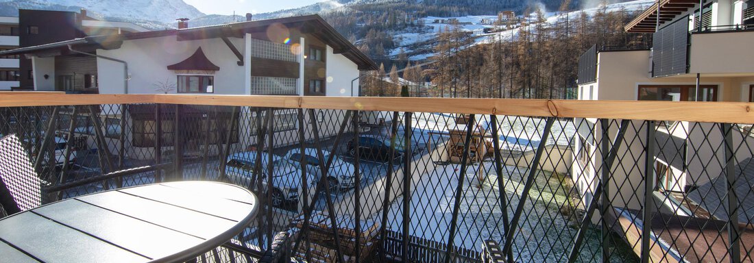 A balcony with a view of snow-covered mountains and a clear blue sky. The sun shines over the landscape, inviting relaxation. - Haus Sonnwend - Sölden