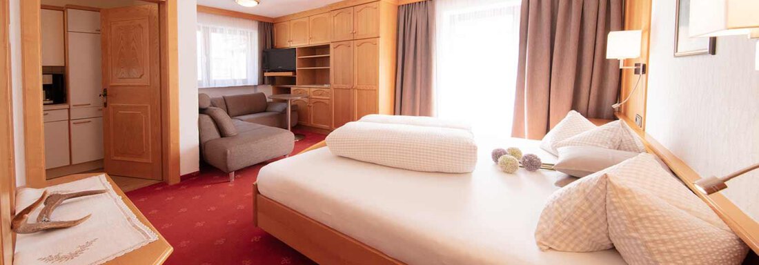 Zimmer | © Haus Sonnwend (CC C) A cozy hotel room with a large bed and a sitting couch. The decor is bright and inviting, with warm colors and plenty of natural light. - Haus Sonnwend - Sölden