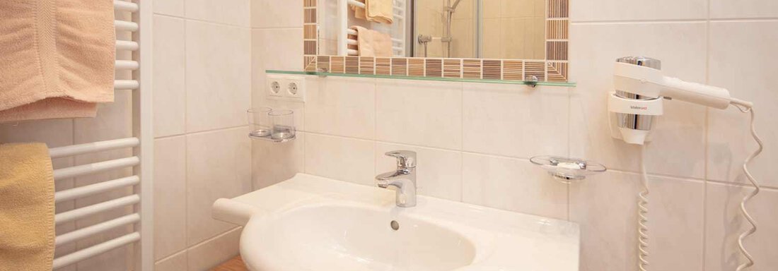 A modern bathroom with a sink and a large mirror. Towels are neatly hung on a towel rack. - Haus Sonnwend - Sölden