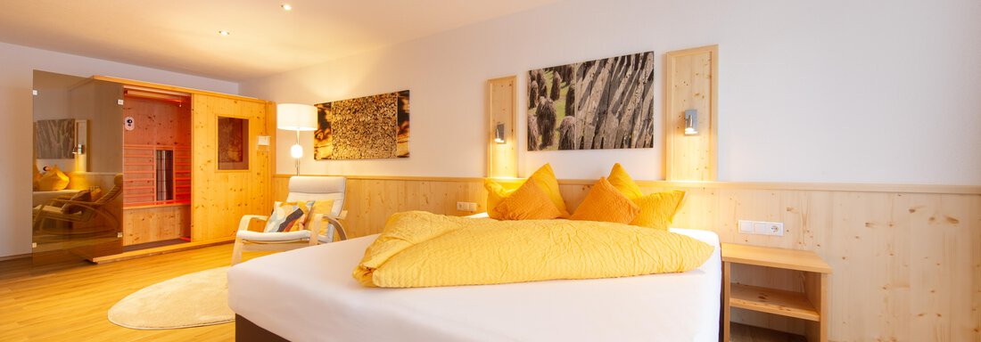 App. 7-1 A modern bedroom with a large bed and bright yellow pillows. The room features wooden details and a cozy atmosphere. - Haus Stefanie - Sölden