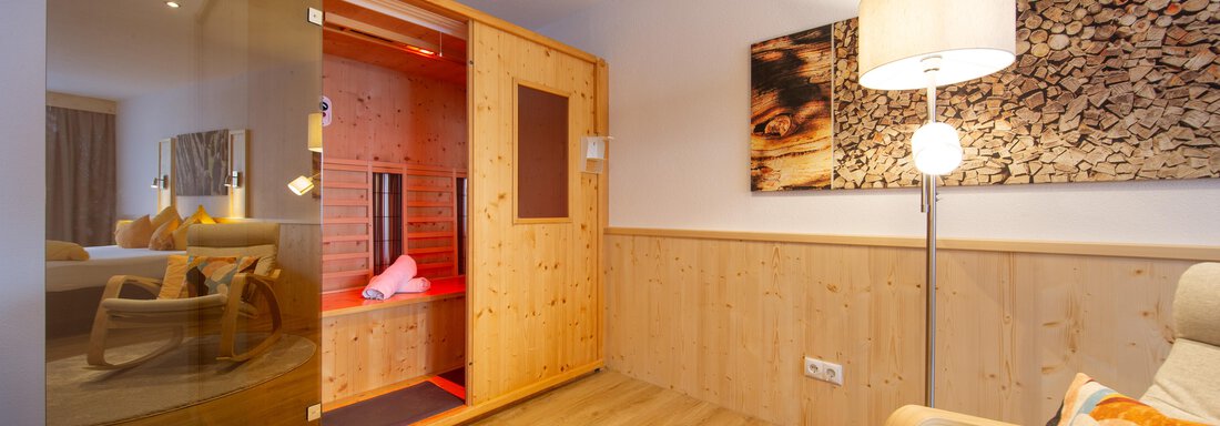 A modern room with a sauna and warm wooden paneling. A cozy atmosphere with a chair and decorative cushions. - Haus Stefanie - Sölden