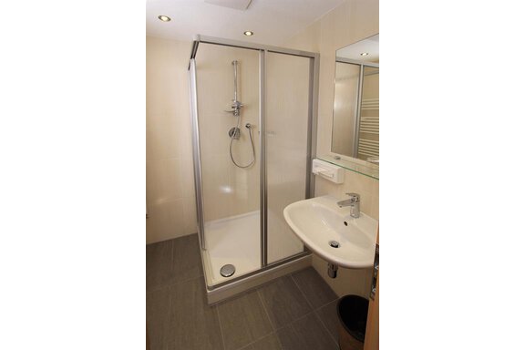 A modern bathroom with a shower cubicle and a sink. The tiles are in neutral colors. - Haus Stefanie - Sölden