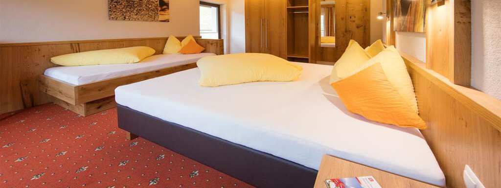 Dreibettzimmer A cozy room with two single beds and bright pillows. The wooden details and the carpet create a warm atmosphere. - Haus Stefanie - Sölden