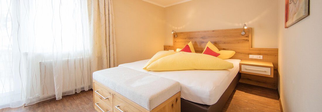 A bright bedroom with a large double bed and a cozy decor. The walls are in neutral colors, and the room has large windows that let in plenty of daylight. - Haus Stefanie - Sölden