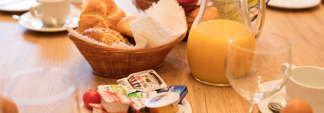 A laid breakfast table with fresh croissants, fruit, and a pitcher of orange juice. There are also eggs and various jams on the table. - Haus Stefanie - Sölden