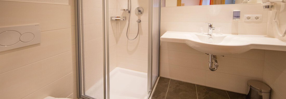 A modern bathroom with a glass shower and a sink. The tiles are in a dark color scheme and the walls are designed in light shades. - Haus Stefanie - Sölden