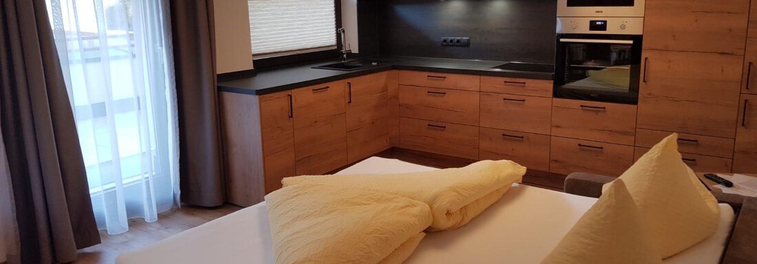 A modern room with a cozy bed and a small kitchenette. Large windows let in plenty of daylight. - Haus Stefanie - Sölden