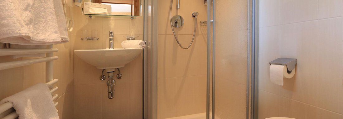 A small, modern bathroom with a shower, a sink, and a toilet. White towels and a pleasant color scheme create a clean atmosphere. - Haus Stefanie - Sölden