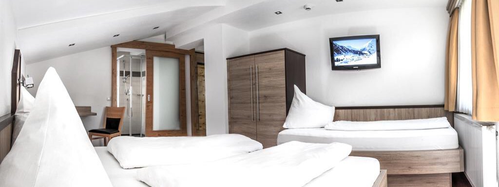 A cozy room with two single beds and modern furniture. A television and large windows create a bright and inviting atmosphere. - Haus Tanja - Sölden