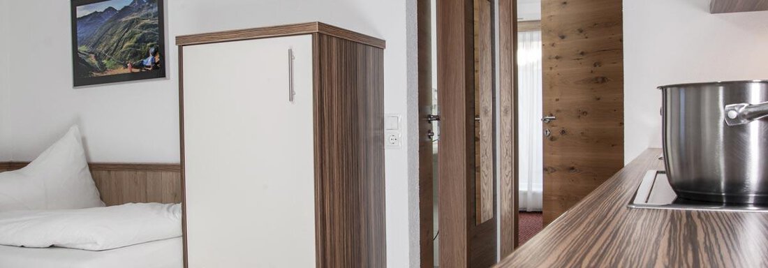 A modern room with wooden furniture and a cool refrigerator. In the background, doors and a window are visible. - Haus Tanja - Sölden