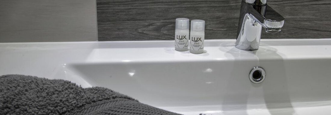 A modern bathroom with a bathtub and a faucet. Two bottles of care products are next to the tub. - Haus Tanja - Sölden