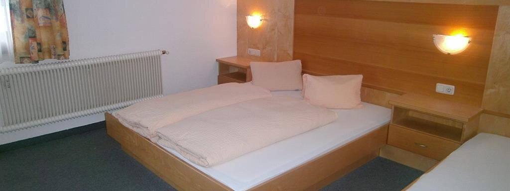 Dreibettzimmer A simply furnished room with a double bed and a single bed. Light wood-colored furniture and carpeted flooring create a calm atmosphere. - Hirschenhof - Sölden