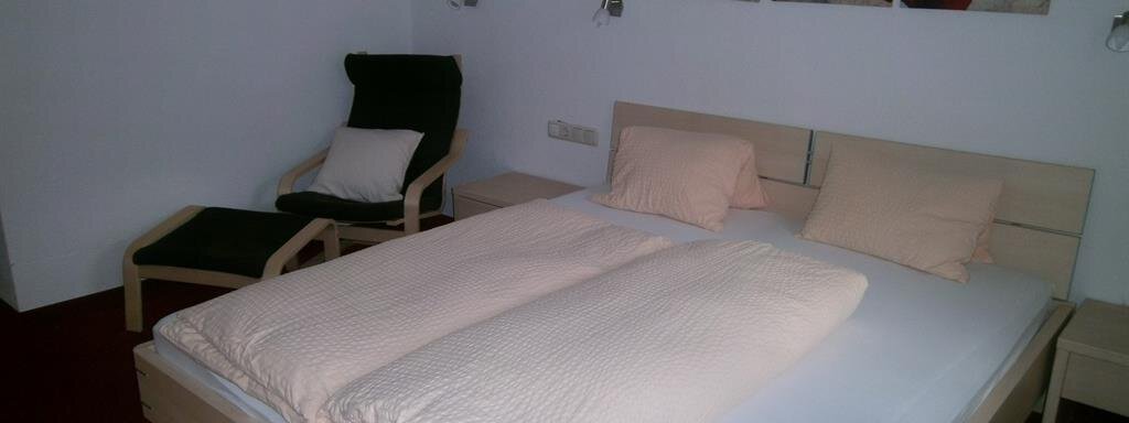 Doppelzimmer A cozy bedroom with a large double bed and beige bedding.
Next to the bed is a chair and pictures of red poppies hang on the wall. - Hirschenhof - Sölden
