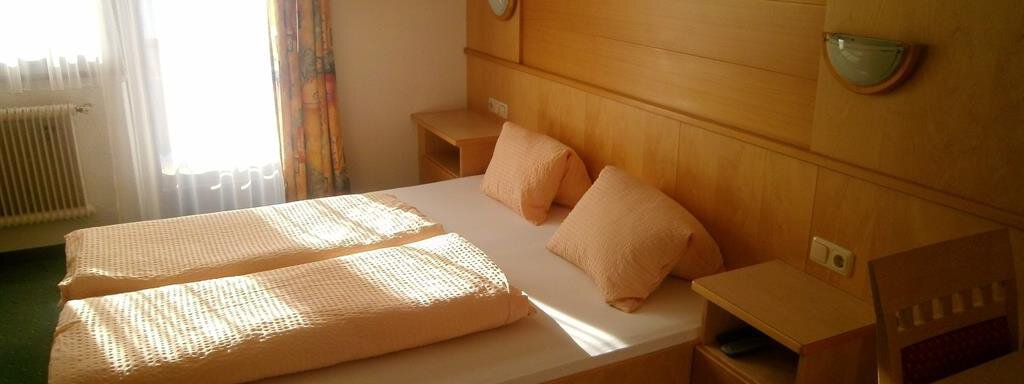 A cozy bedroom with a double bed and light cushions. The room has large windows that let in plenty of light. - Hirschenhof - Sölden