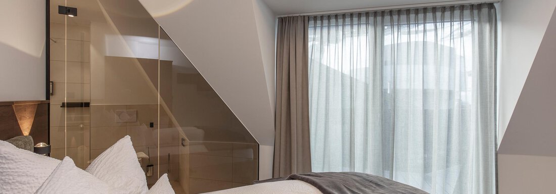 A modern bedroom with two beds and large windows. The light curtains let in plenty of light and create a pleasant atmosphere. - Home4You - Sölden