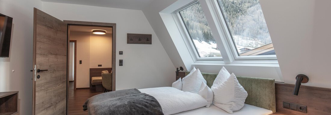 A bright bedroom with two beds and large windows. The modern décor and wooden floor create a cozy atmosphere. - Home4You - Sölden