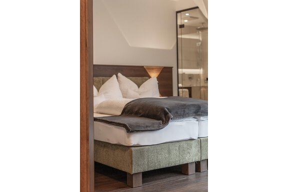 A modern bedroom with a cozy bed and elegant bedding. The decor is stylish and well-lit. - Home4You - Sölden