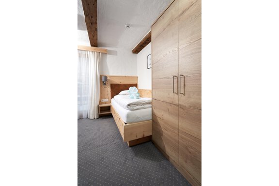A modern room with wooden details and a comfortable bed. The room has large windows and a practical wardrobe. - Hotel am Hof - Sölden