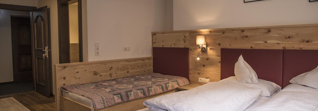 A cozy room with two wooden beds. The walls are plain, and there is soft lighting as well as a sturdy floor. - Hotel am Hof - Sölden